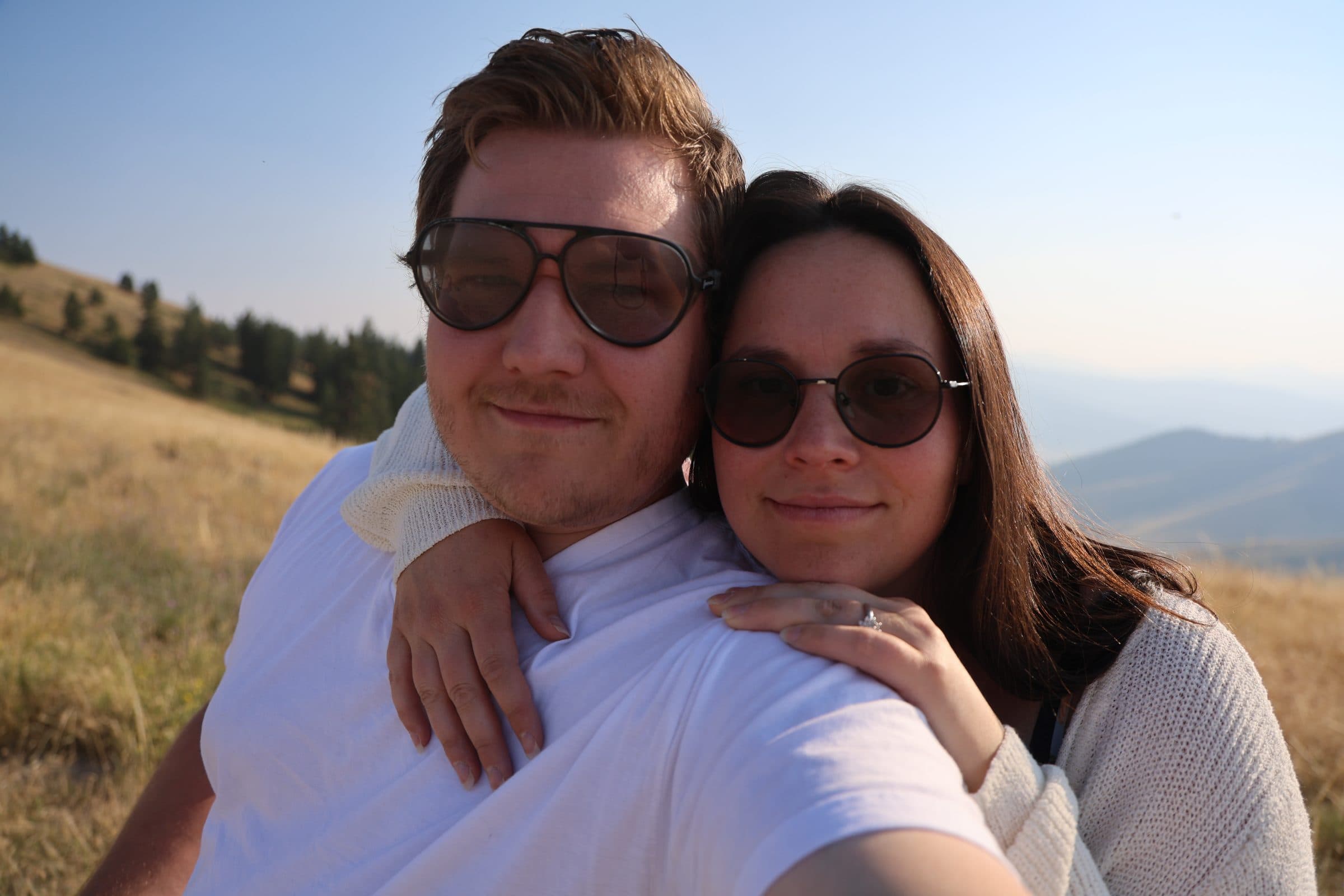 Colten and Mackenzie Krauter on a golden hillside at sunset, Montana ranges behind them